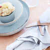 A muffin on a plate, topped with a Lind DNA Napkin Loop (Set of 4).
