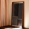 A limited-edition ATELIER PLATEAU mirror hanging on a wall next to a curtain.