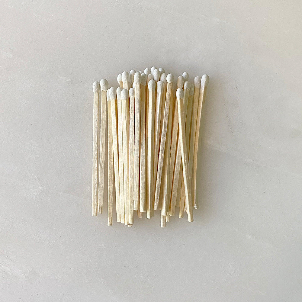 A bunch of handmade HOUSE OF GOOD wooden match sticks on a white surface.