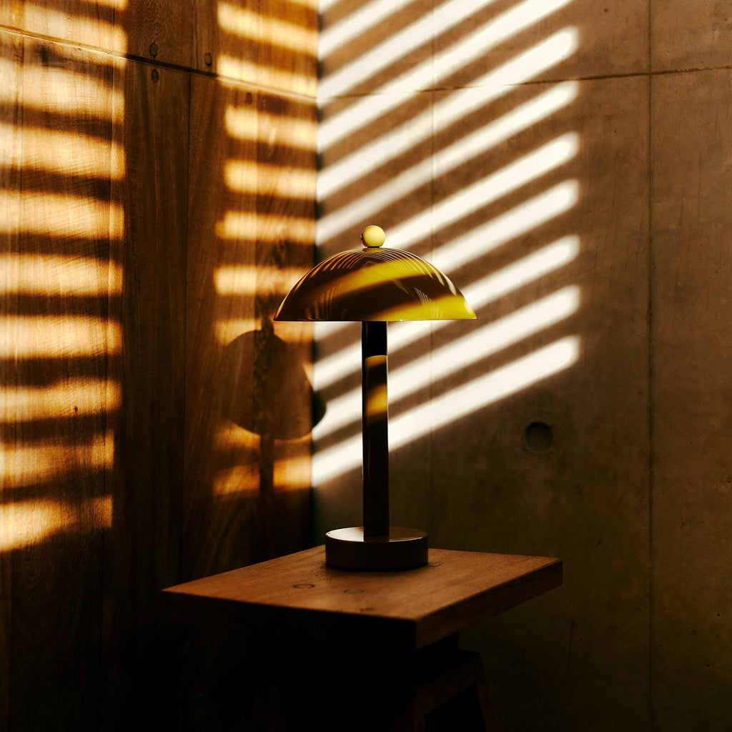 A DUNE table lamp by IN COMMON WITH is sitting on a table in front of a wooden wall.
