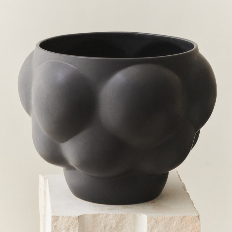 A black Ceramic Balloon Bowl 06 sitting on top of a pedestal - LOUISE ROE.