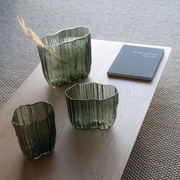 Three MELT VASES by ANTREI HARTIKAINEN on a table next to a book.