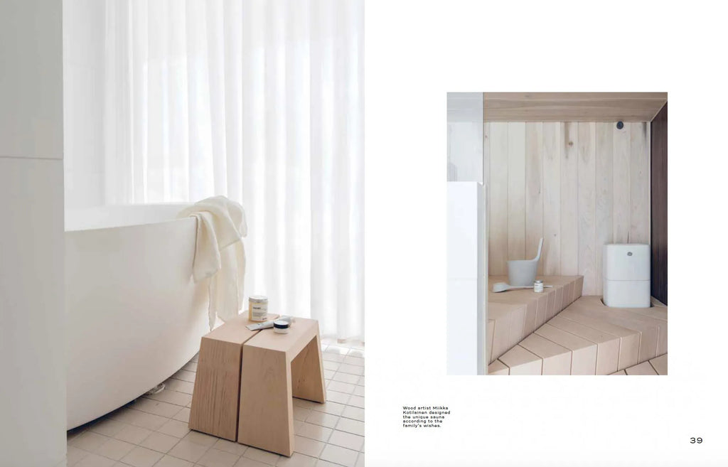 A magazine spread showing a bathroom with a Cozy Nordic Interior Book and a bathtub and stool.