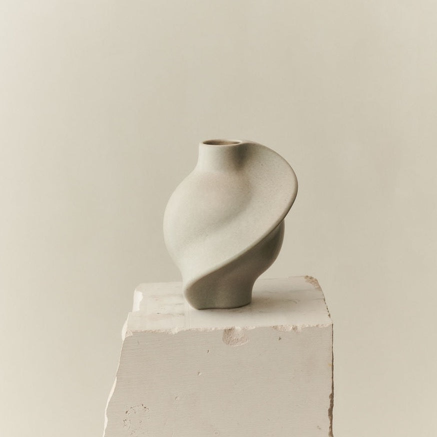 A PIROUT VASE VINTAGE GLAZE by LOUISE ROE displayed on top of a block of concrete.