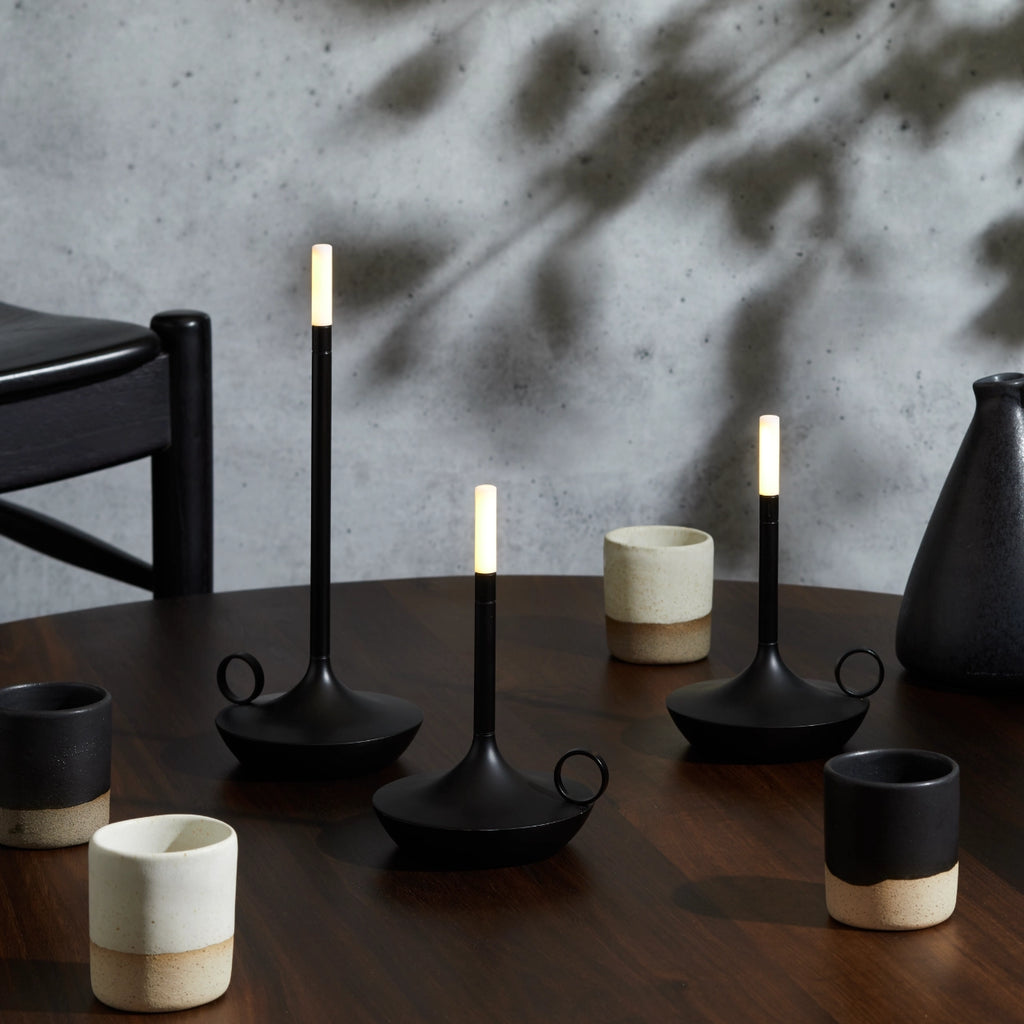 Four Graypants WICK PORTABLE LAMP candle holders on a wooden table.