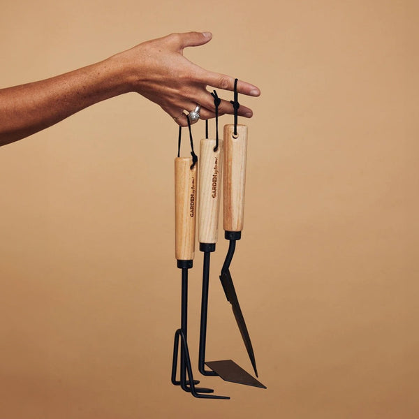 A person holding a Benson garden hand tool set on a beige background.