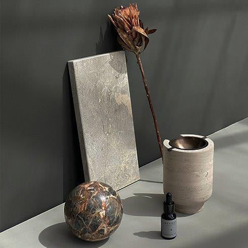 An Aura Oil Burner by Brandt Collective with a beautiful flower sitting on a table.