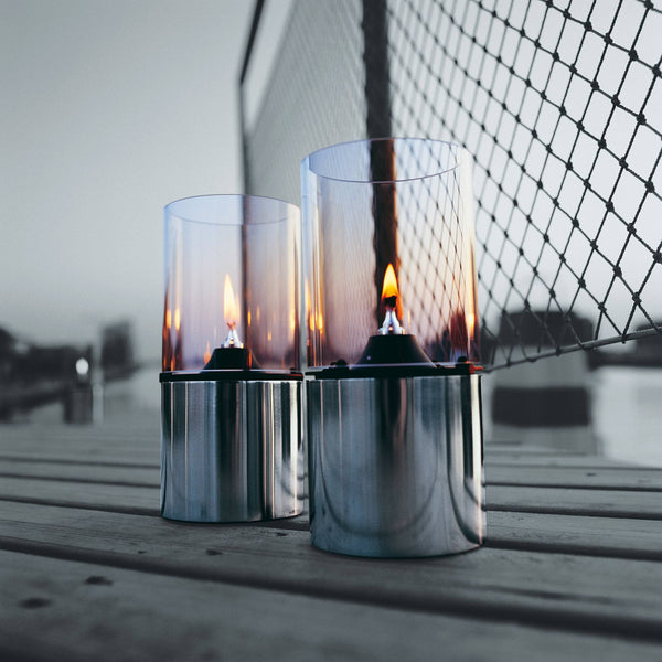 Two STELTON EM OIL LAMP holders on a wooden deck.