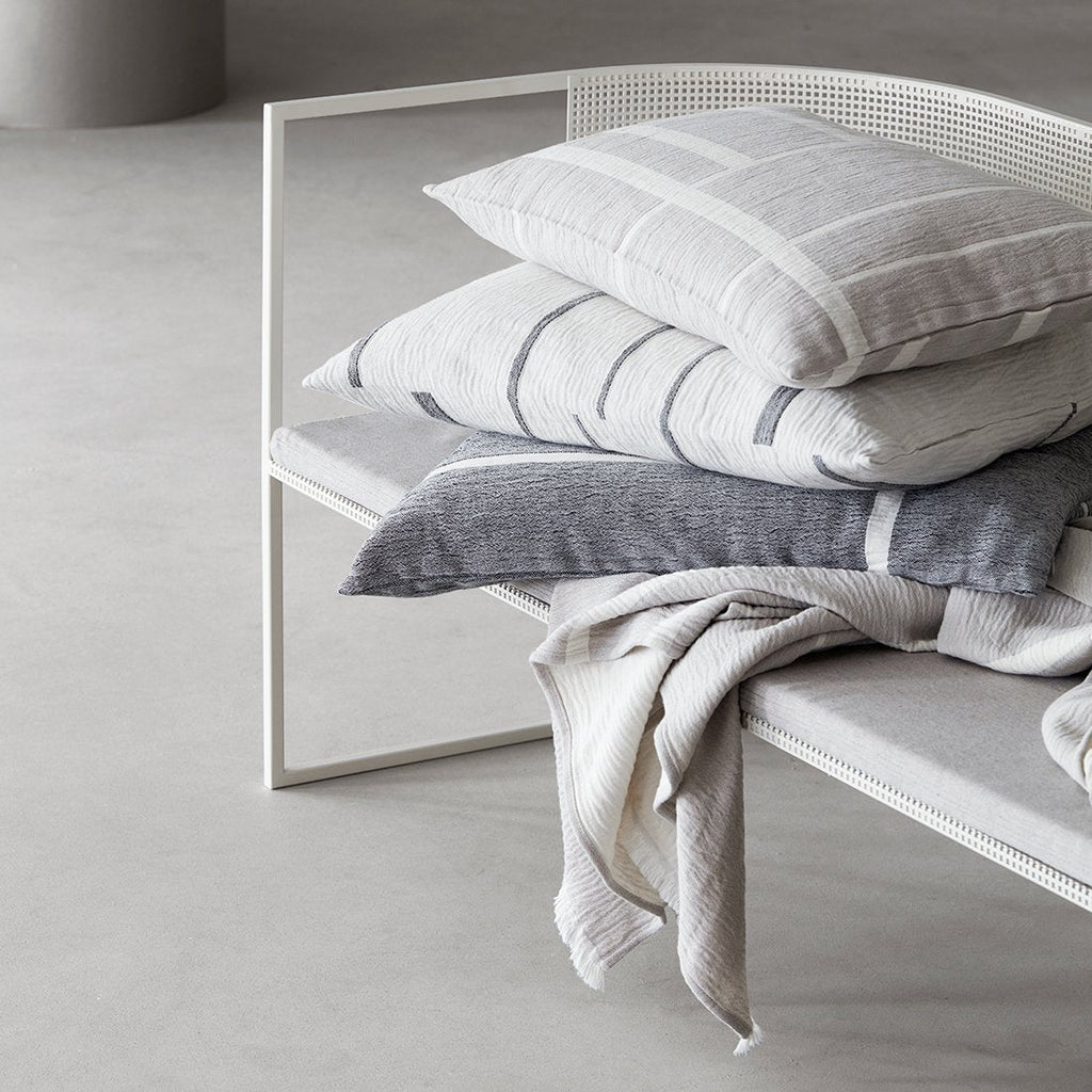 A bench with ARCHITECTURE CUSHION pillows and blankets on it from KRISTINA DAM STUDIO, inspired by Gestalt Haus.