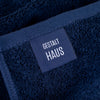 A blue BATH SHEET with a label that says GESTALT HAUS.