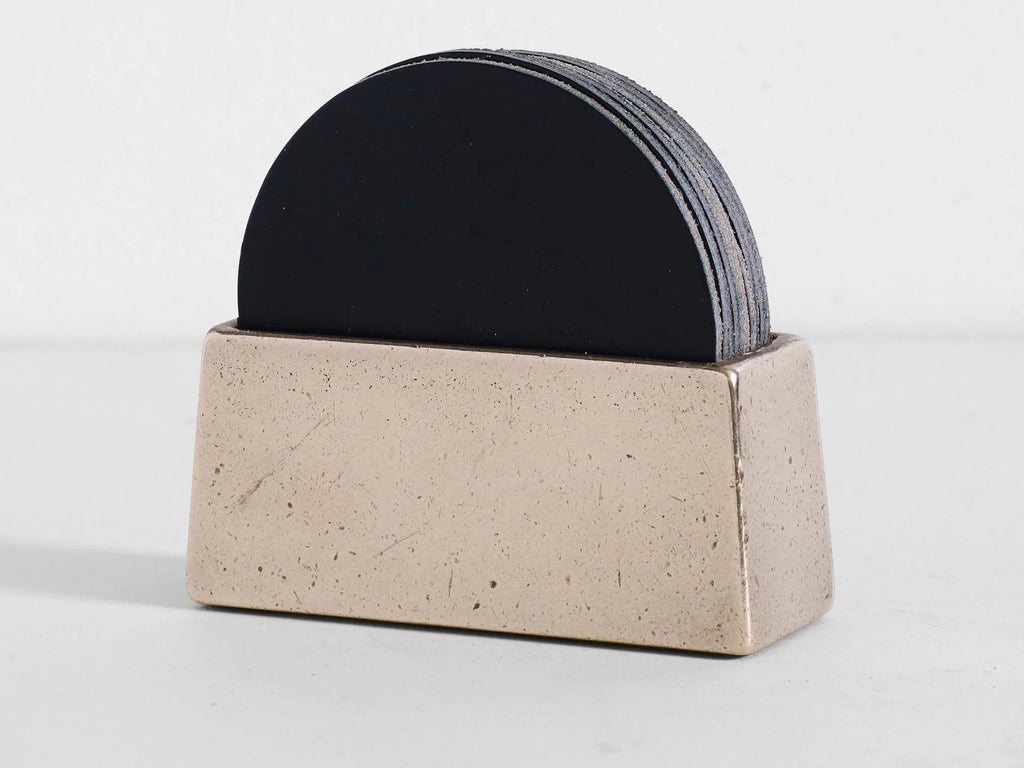 A black Studio Henry Wilson Coaster Holder with Coasters on a white surface.