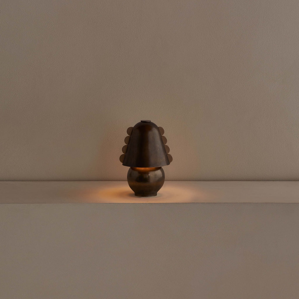 A CALLA TABLE LAMP by IN COMMON WITH sits on a table in front of a wall at Gestalt Haus.