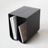 A black CURVED SIDE TABLE with a book inside of it from KRISTINA DAM STUDIO, inspired by Gestalt principles.