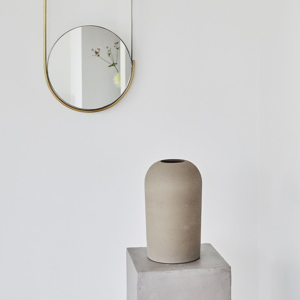 A KRISTINA DAM STUDIO DOME VASES, inspired by the Gestalt Haus movement, sits on a pedestal next to a mirror.