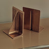 Two BRASS BOOKENDS by STUDIO HENRY WILSON on a table.