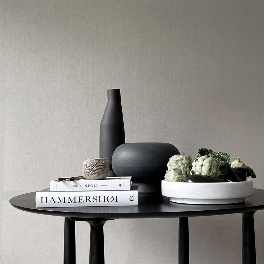 A black FORMALISM BOWL with a book and a vase by 101 COPENHAGEN that embodies the essence of Gestalt Haus.