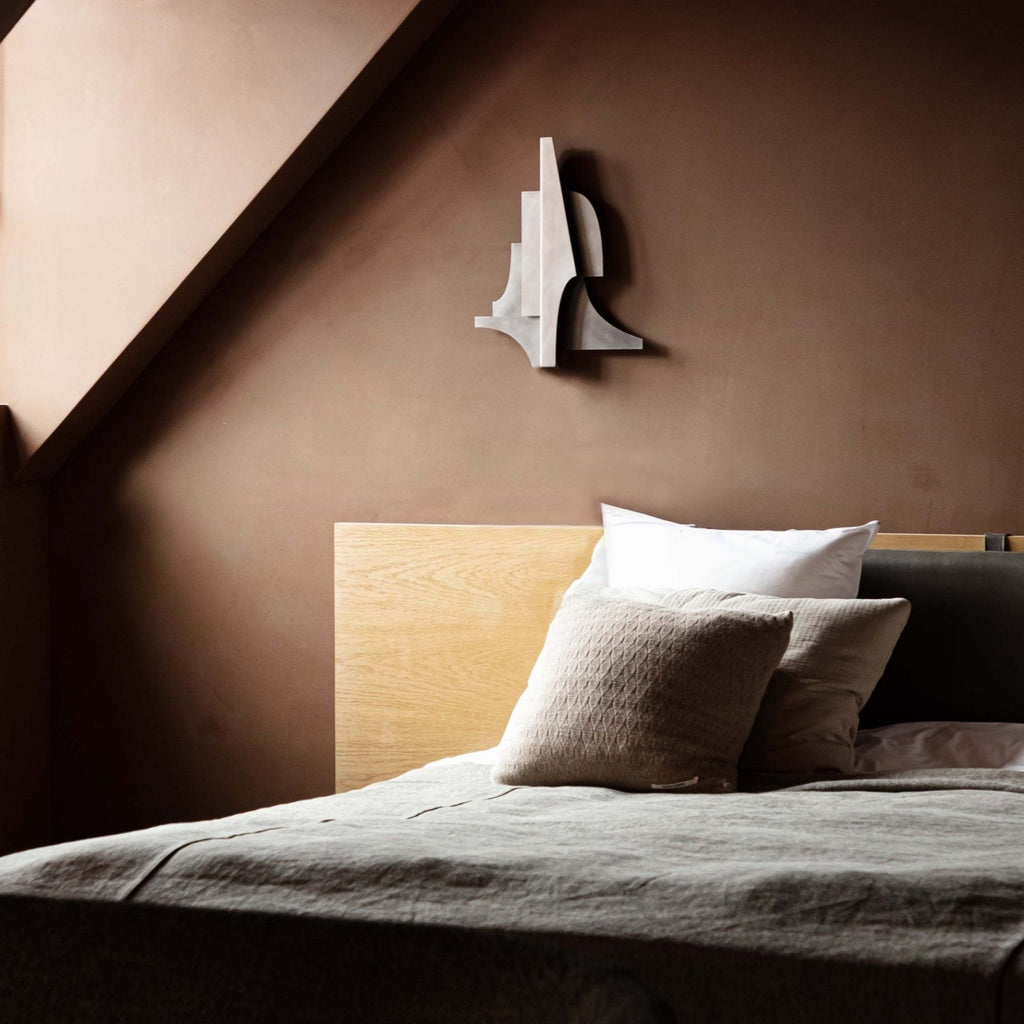 A Gestalt Haus bed in a room with brown walls, designed by ATELIER PLATEAU.