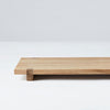 A small Japanese wood board tray on a white surface, made by Kristina Dam Studio, with Gestalt influence.