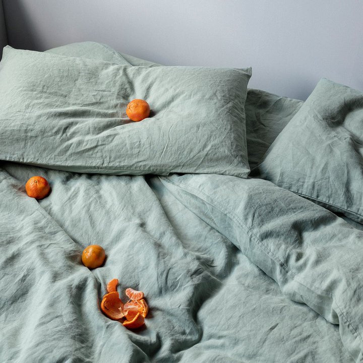 A Gestalt Haus LINEN DUVET COVER from CULTIVER adorned with pillows and oranges.
