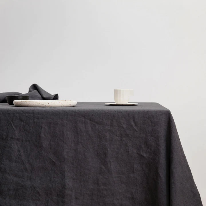 A black CULTIVER linen tablecloth on a wooden table at Gestalt Haus.
