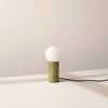 An ORB TABLE LAMP from Gestalt Haus with a green shade and a white cord.