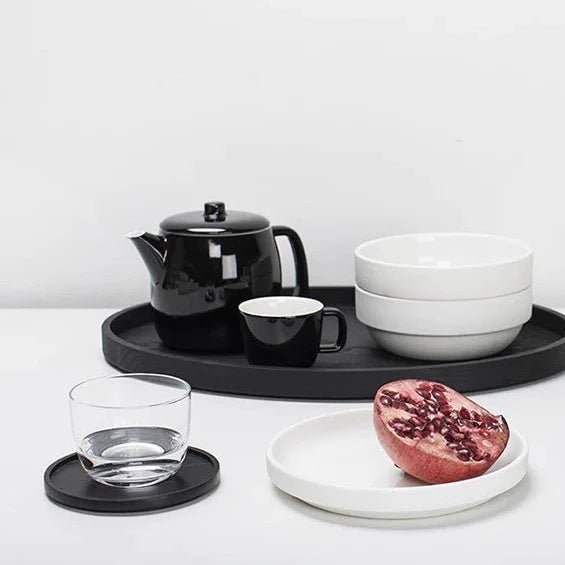 A black tray with Gestalt Haus coasters by Vincent Van Duysen on it, by Serax.