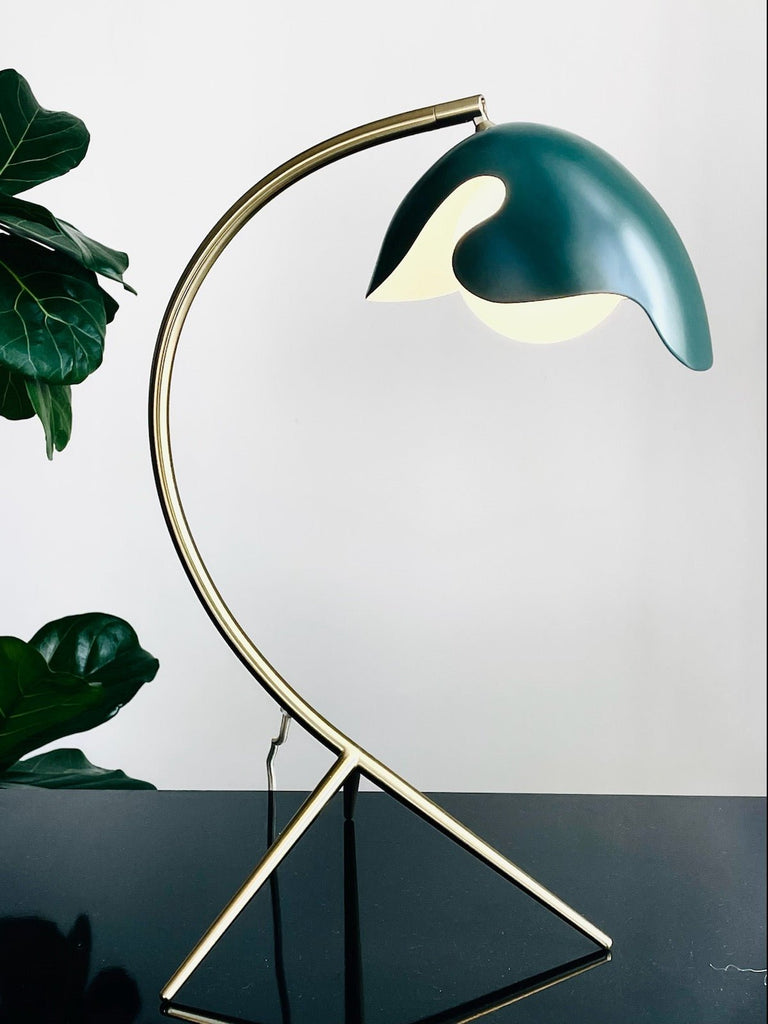 A PS38 TABLE LAMP with a green leaf on it, made by ATBO, inspired by the minimalist aesthetics of Gestalt Haus.