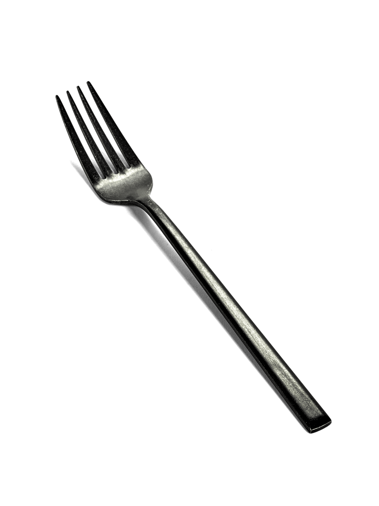 A black PURE FLATWARE BY PASCALE NAESSENS fork on a green background, made by SERAX at Gestalt Haus.