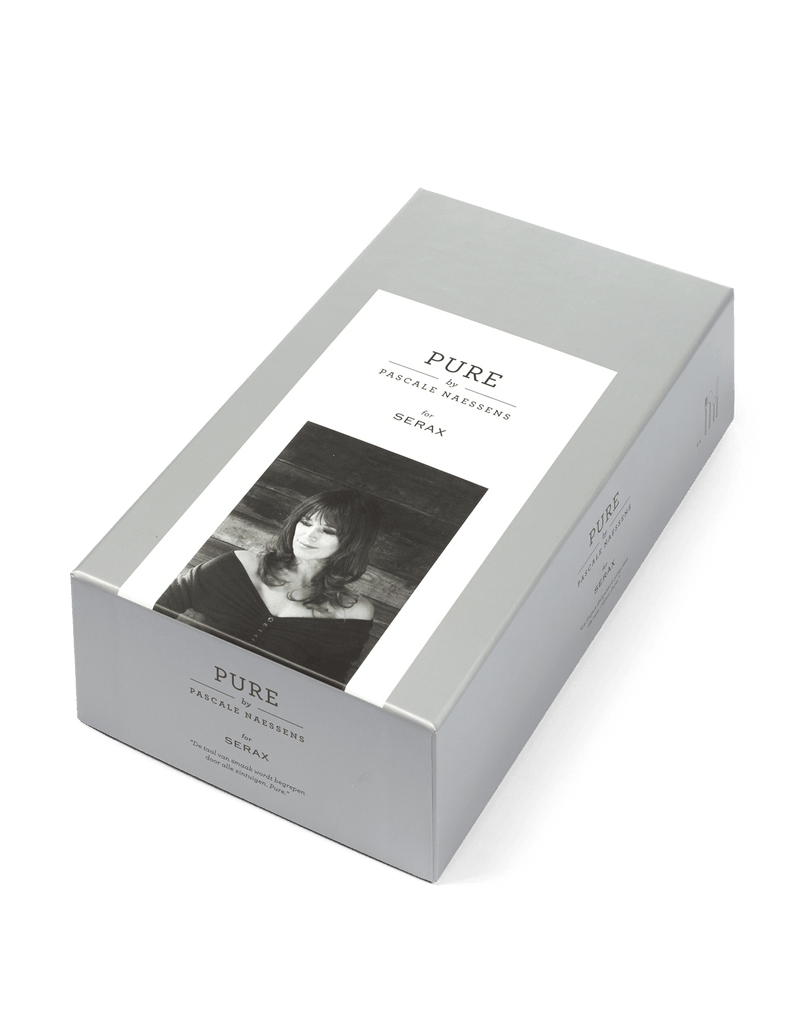 A black and white photo of a woman holding PURE FLATWARE BY PASCALE NAESSENS, manufactured by SERAX, in a Gestalt Haus box.
