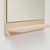 A FORM & REFINE wooden shelf with a RIM WALL MIRROR hanging on it in Gestalt Haus style.
