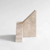An ORIGIN MADE sculpture of a staircase made of travertine on a white surface, called SPIRAL Gestalt Haus Sculpture.
