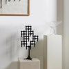 A monochrome STOFF NAGEL sculpture sits on a pedestal in front of a painting.