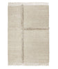 A beige E-1027 rug with fringes on a white background by Sera Helsinki, inspired by Gestalt design principles.