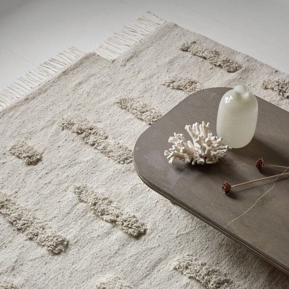 A Gestalt Haus table showcasing a Laine Rug by Sera Helsinki embellished with a vase.