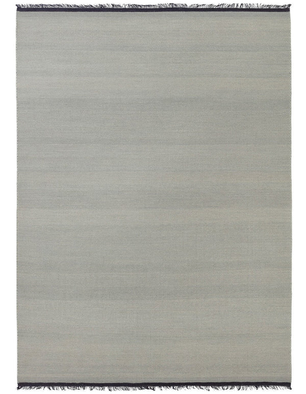 A grey NJORD rug with fringes on a white background from the brand FABULA LIVING, inspired by Gestalt Haus.