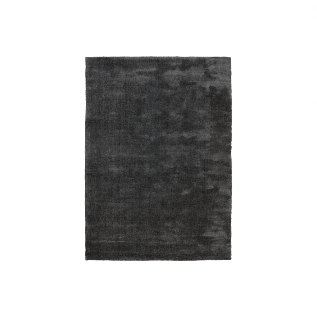 A black Gestalt Haus rug on a white background by FABULA LIVING.