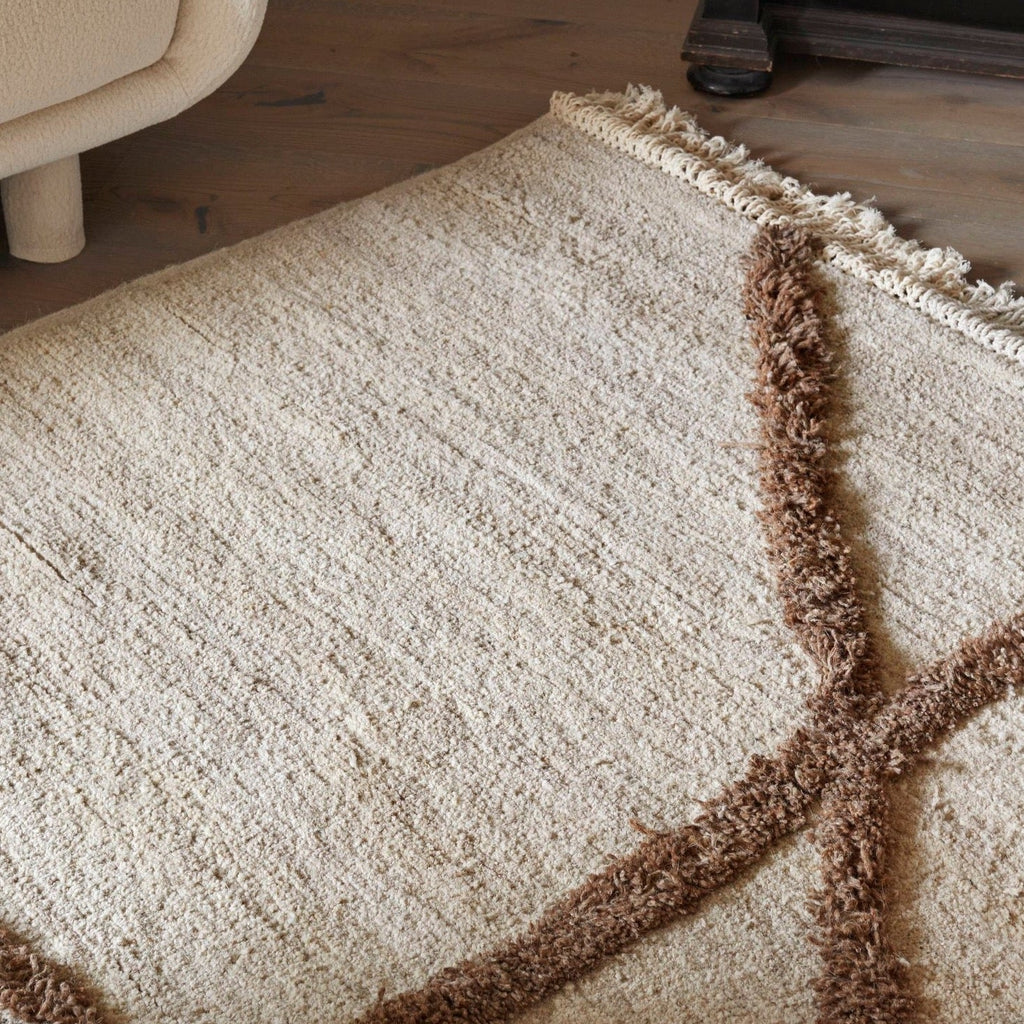 A Gestalt Haus rug with fringes on top of a wooden floor.