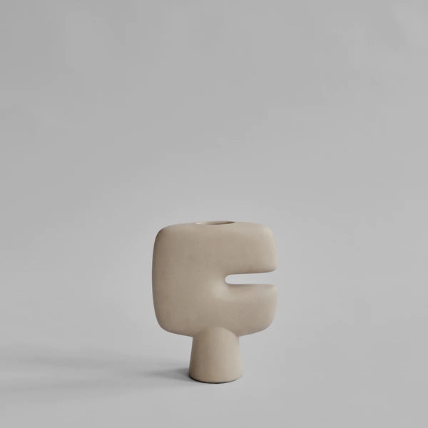 A white TRIBAL VASE with a curved shape, sitting on a grey surface, by 101 COPENHAGEN.