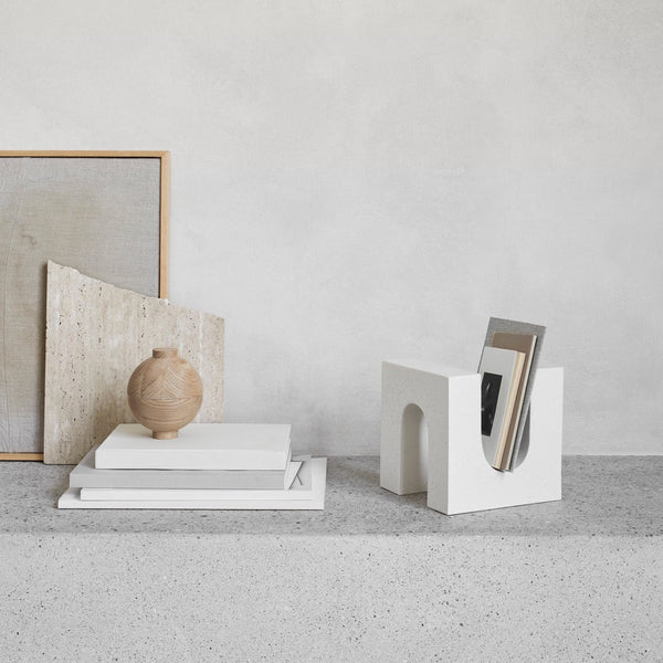 A white BRICK SCULPTURE shelf with books and a porcelain vase on it, made by KRISTINA DAM STUDIO.