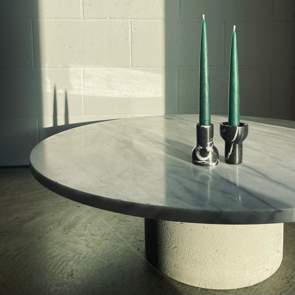 A coffee table adorned with a Aaron Probyn Taper Candle Holder holding two COMO TEA LIGHT candles on top, designed by Aaron Probyn.