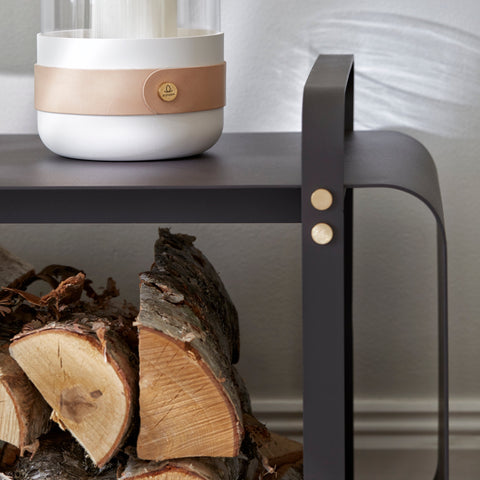 An ELDVARM NINNE WOOD BENCH with logs and a candle on it.