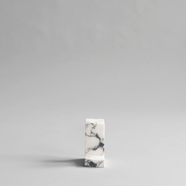 A small BRICK CANDLE HOLDER from 101 COPENHAGEN sitting on top of a grey surface, serving as a candle holder.