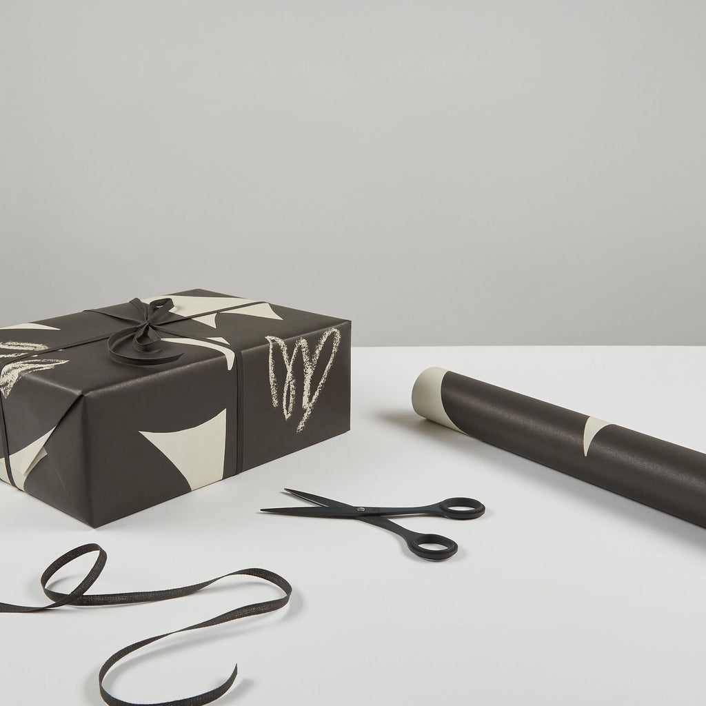 A black and white AEAND PETAL WRAPPING PAPER with scissors next to it from the brand KINSHIPPED.