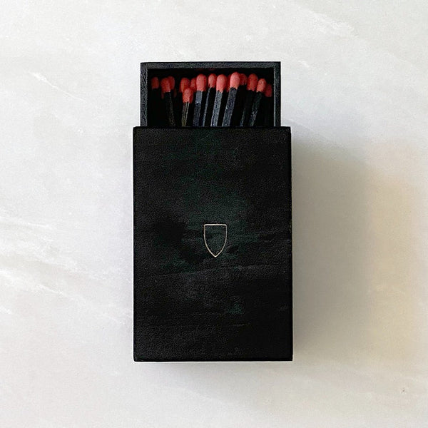 Handmade House of Good wooden matchboxes in a black box on a white surface.