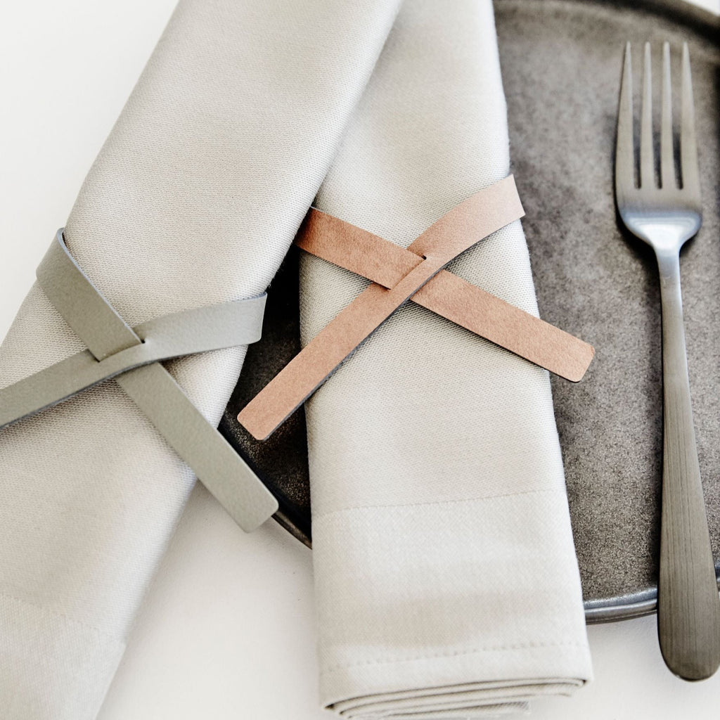 Two NAPKIN LOOP (SET OF 4) by LIND DNA on a plate with a knife and fork, placed elegantly on a dinner table.