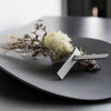A black plate with dried flowers on a LIND DNA NAPKIN LOOP (SET OF 4).