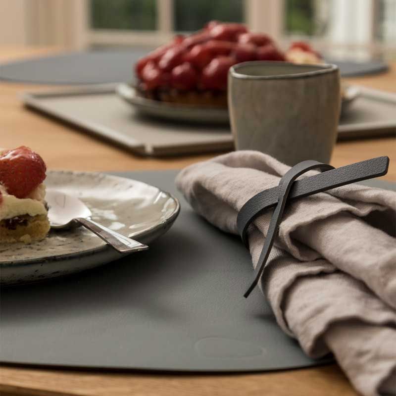 A LIND DNA NAPKIN LOOP (SET OF 4) placemat on a dinner table next to a plate of strawberries.