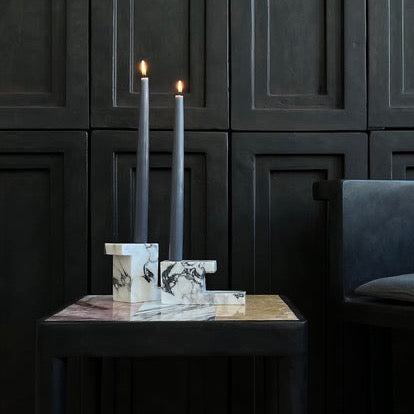 Two BRICK CANDLE HOLDERS by 101 COPENHAGEN on a table in front of a solid black wall.