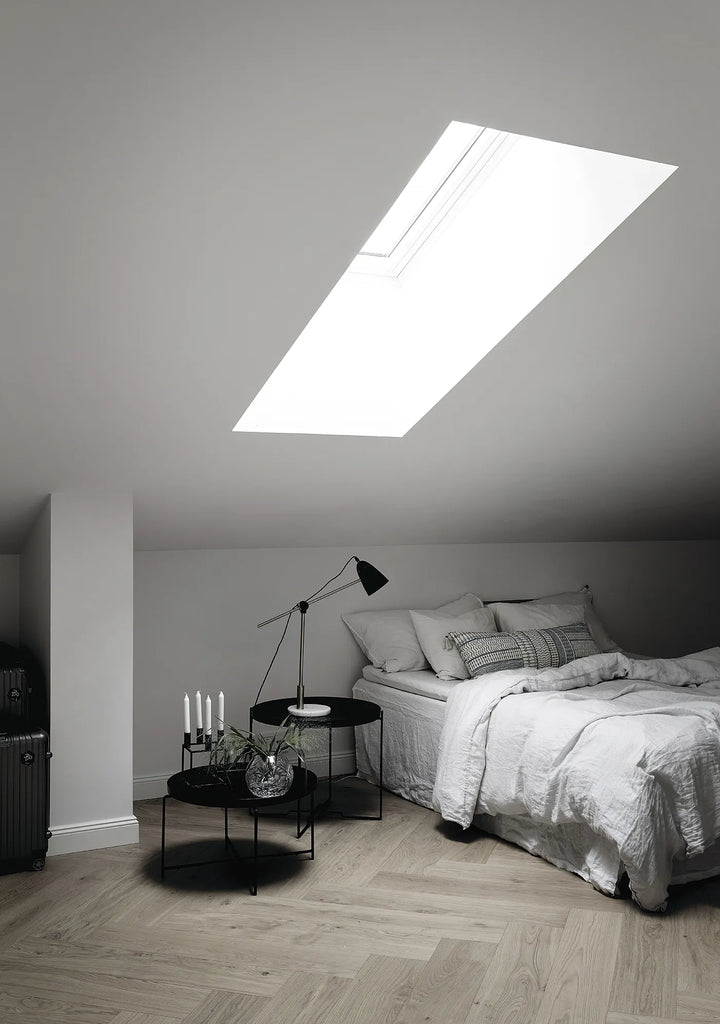 A bedroom with a COZY skylight in the ceiling.