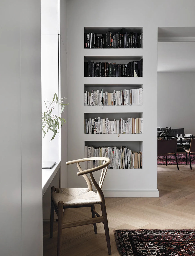 A room with HAPPY HOMES - CREATIVE bookshelves and a chair in front of a window by COZY.